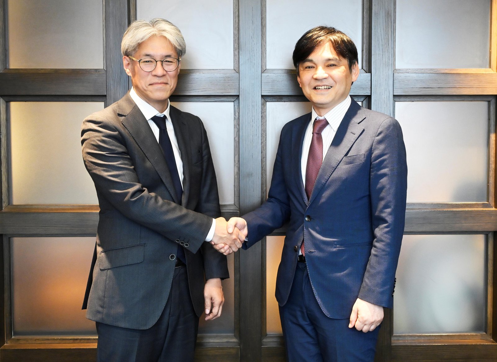 小林修代表と齋藤夏見代表の握手 - 2026年6月1日 経営統合のシンボル